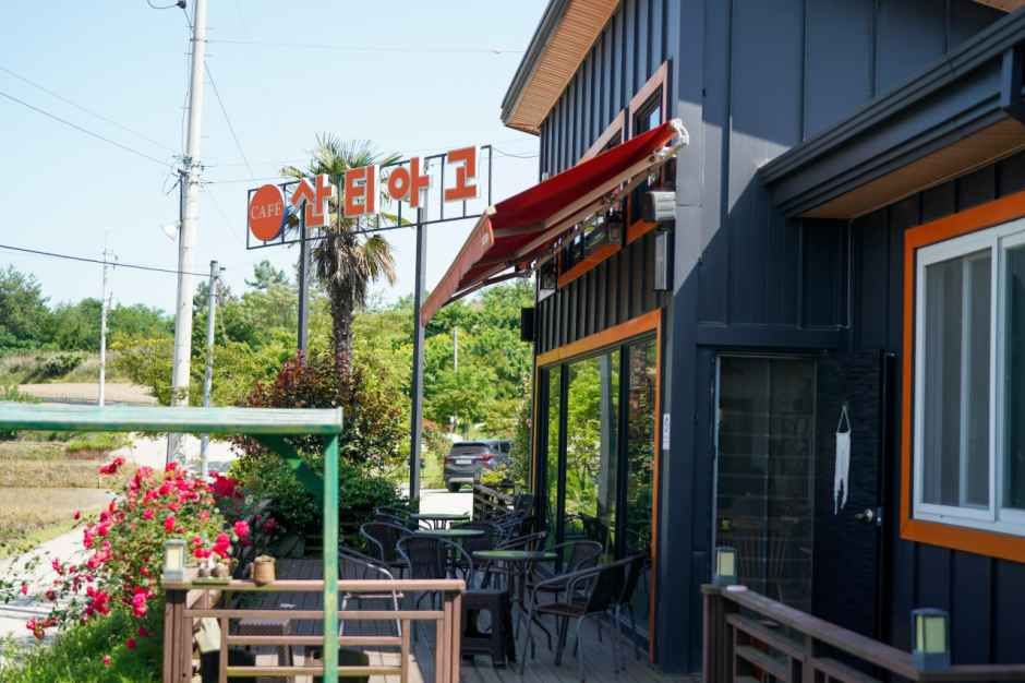 커피농장 산티아고 본점의 간판과 꽃이 놓인 입구, 야외 좌석